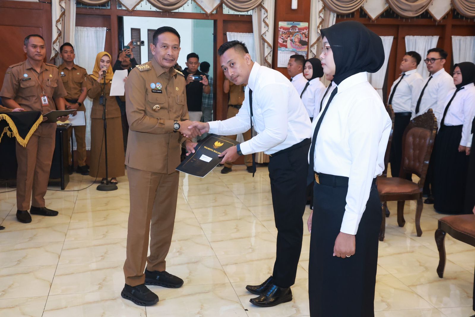 Wali Kota Malang, Dr. Ir. Wahyu Hidayat, M.M, menegaskan bahwa etika birokrasi harus menjadi fondasi utama dalam pelaksanaan tugas para Calon Pegawai Negeri Sipil (CPNS). Hal tersebut disampaikannya saat menyerahkan Surat Keputusan (SK) kepada 50 CPNS formasi tahun 2024 di Ruang Sidang Balai Kota Malang, Selasa (27/5/2025).