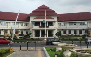 Di tengah geliat pembangunan Kota Malang yang kian dinamis, sebuah bangunan bergaya kolonial tetap berdiri anggun di kawasan Tugu. Gedung Balai Kota Malang, yang kini menjadi pusat pemerintahan kota, menyimpan sejarah panjang yang tak banyak diketahui warga, termasuk kisah tentang jam raksasa yang pernah menghiasi fasad timurnya.